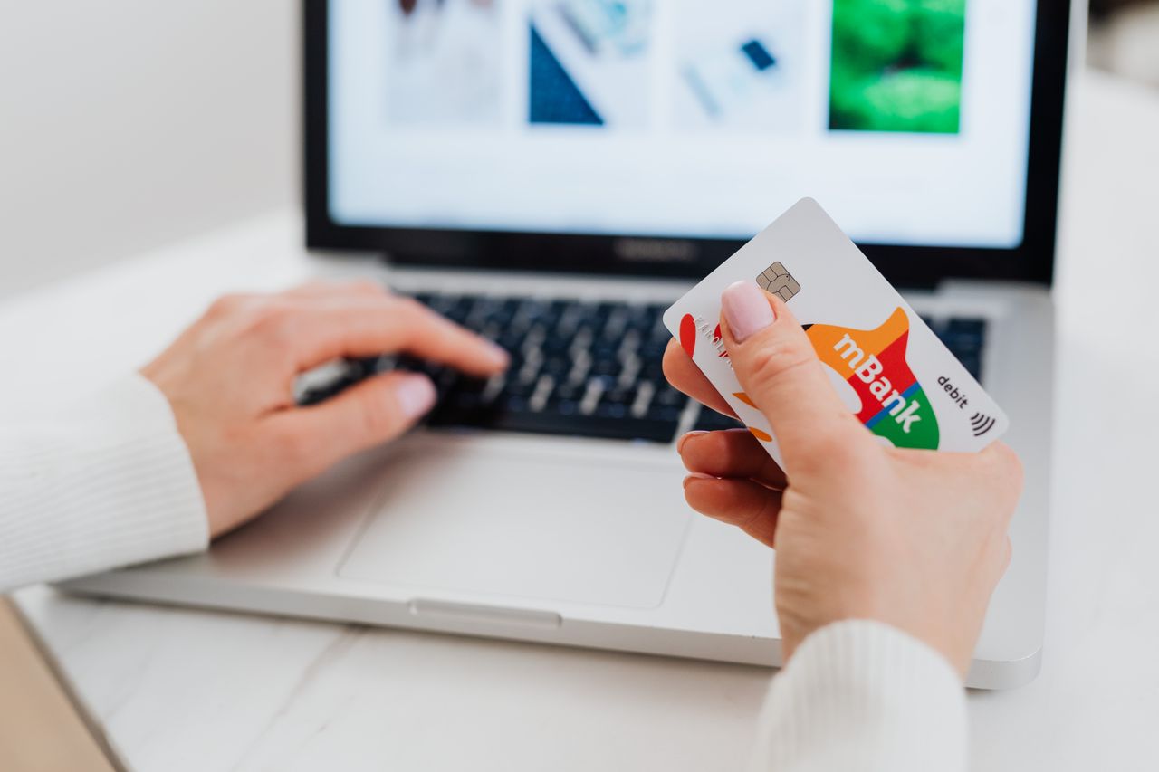 about-bg Close-up of hands using a laptop and holding a credit card for an online transaction.